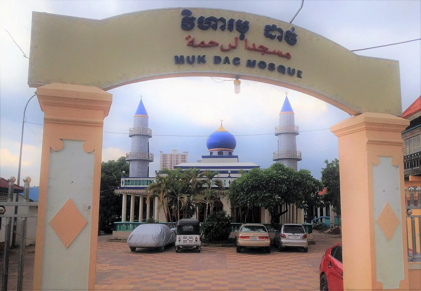 Brama z napisem Muk Dac Mosque, a za nią meczet z niebieską kopułą i dwoma minaretami w dzielnicy Chroy Changvar w Phnom Penh
