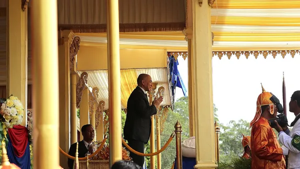 Pawilon królewski podczas Ceremonii Królewskiej Orki w Siem Reap w 2016 r., obok uczestnik w czerwono-złotym stroju ceremonialnym