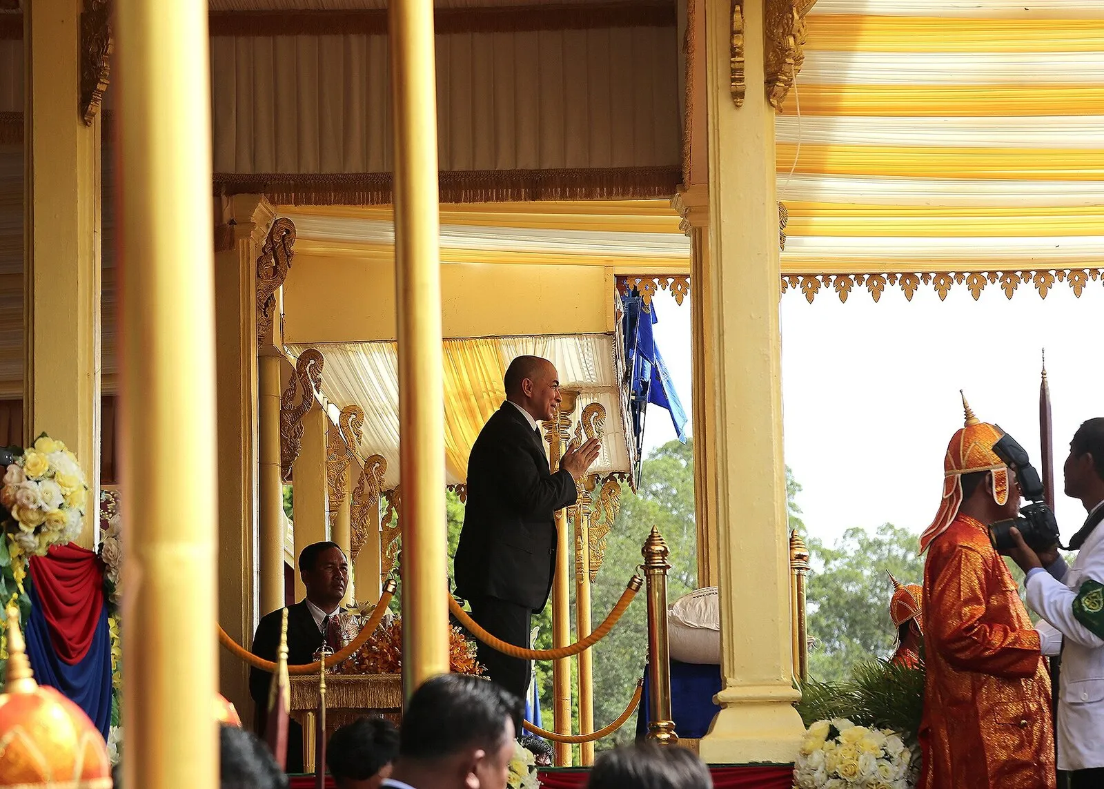 Pawilon królewski podczas Ceremonii Królewskiej Orki w Siem Reap w 2016 r., obok uczestnik w czerwono-złotym stroju ceremonialnym