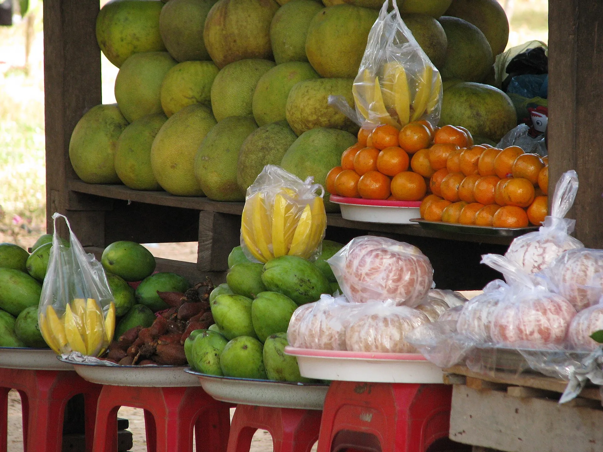 Stragan z pomelo, bananami i pomarańczami na targu przy drodze w Kambodży
