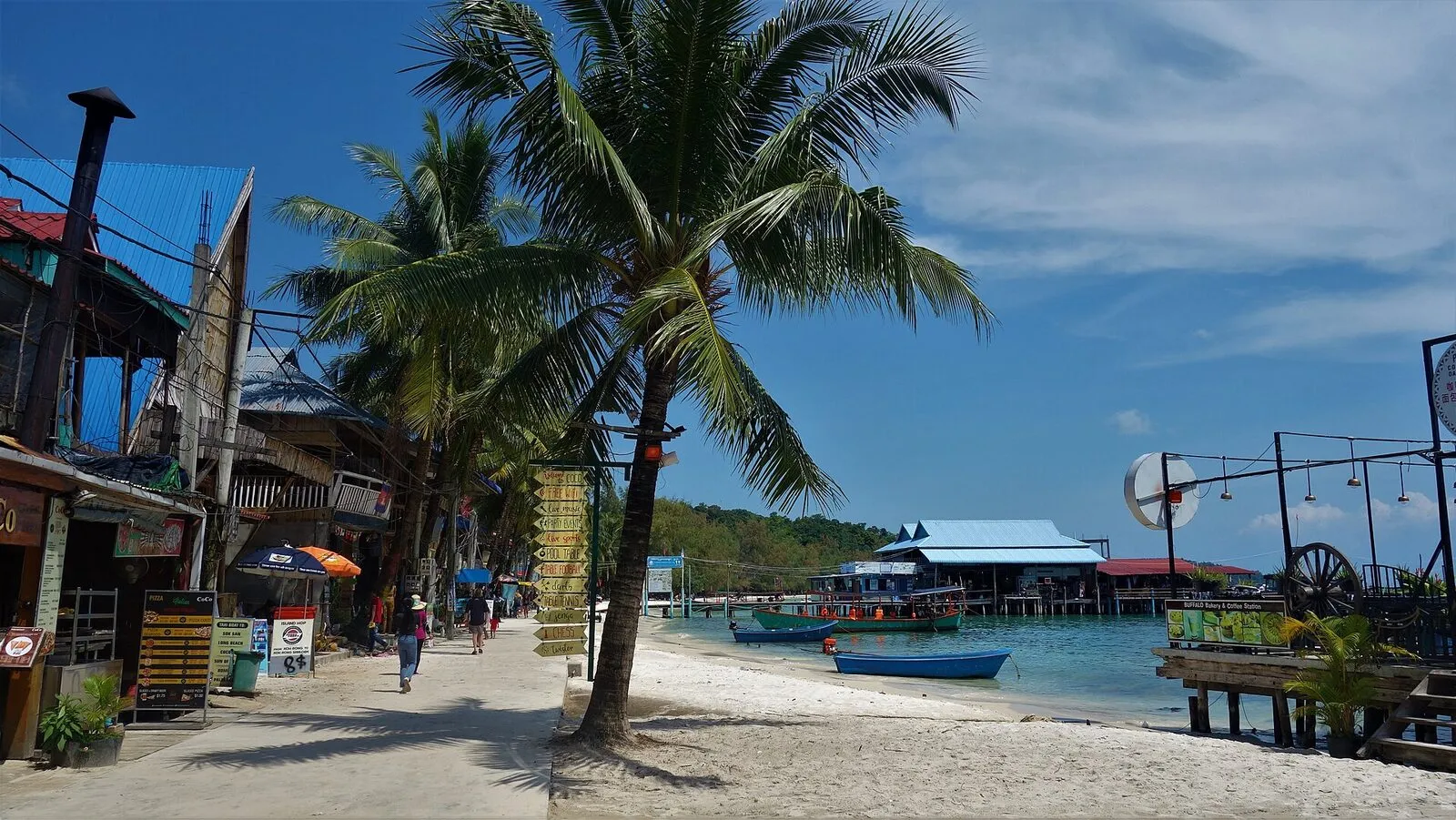 Piaszczysta plaża z palmami i drewnianymi domami nad turkusową wodą na wyspie Koh Rong
