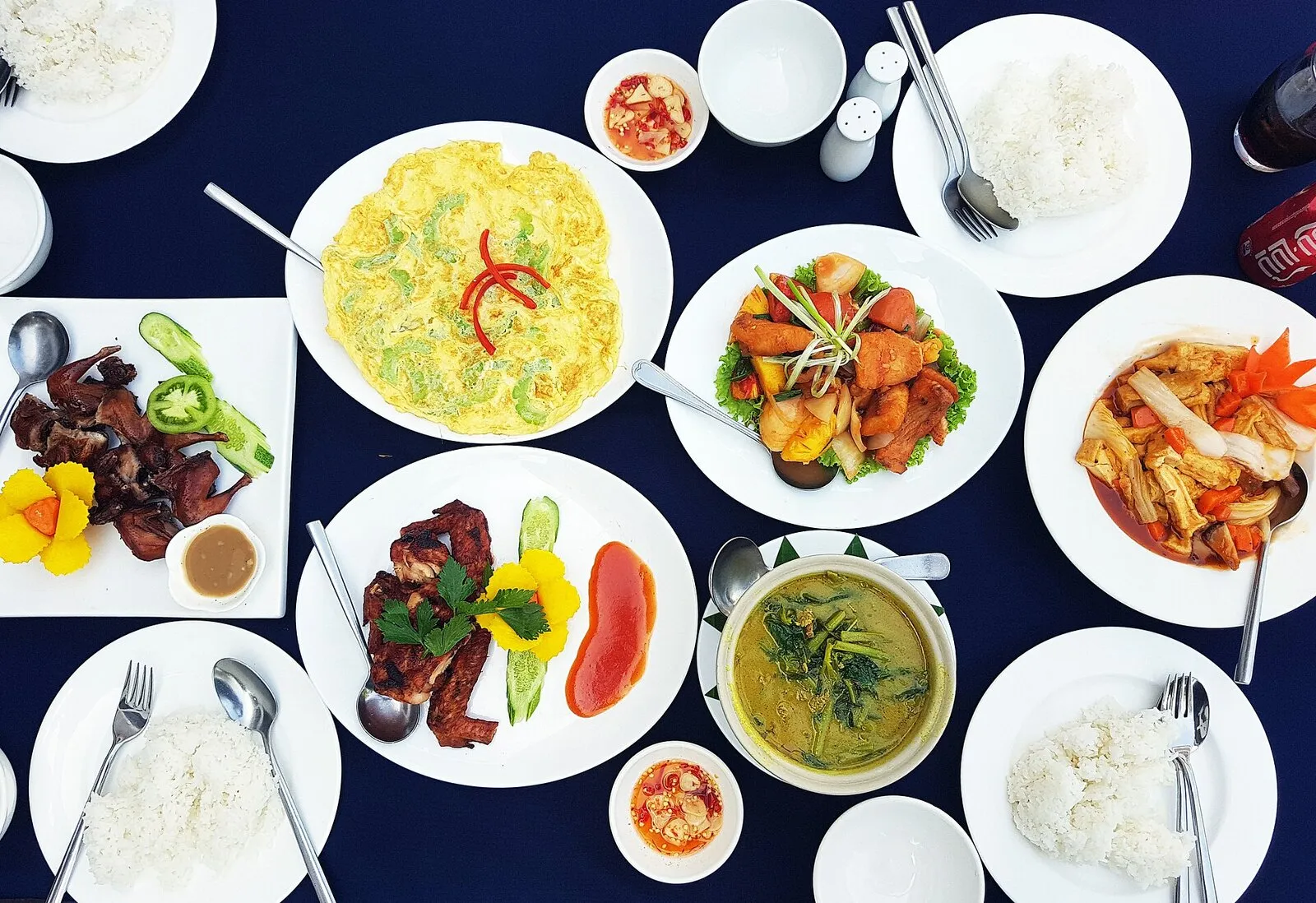 Stół z daniami kuchni khmerskiej: curry, omlet, smażone mięso i ryba, sosy i miseczki ryżu