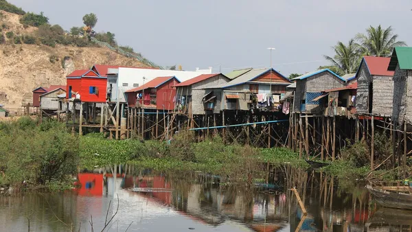 Drewniane i blaszane domy na palach nad rozlewiskiem we wsi przy drodze z Siem Reap nad jezioro Tonle Sap
