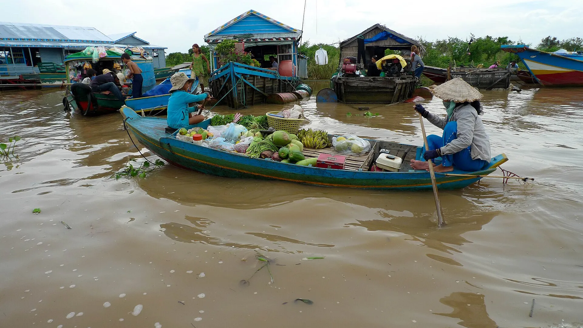 Kobieta wiosłująca łodzią z owocami w pływającej wiosce na jeziorze Tonle Sap