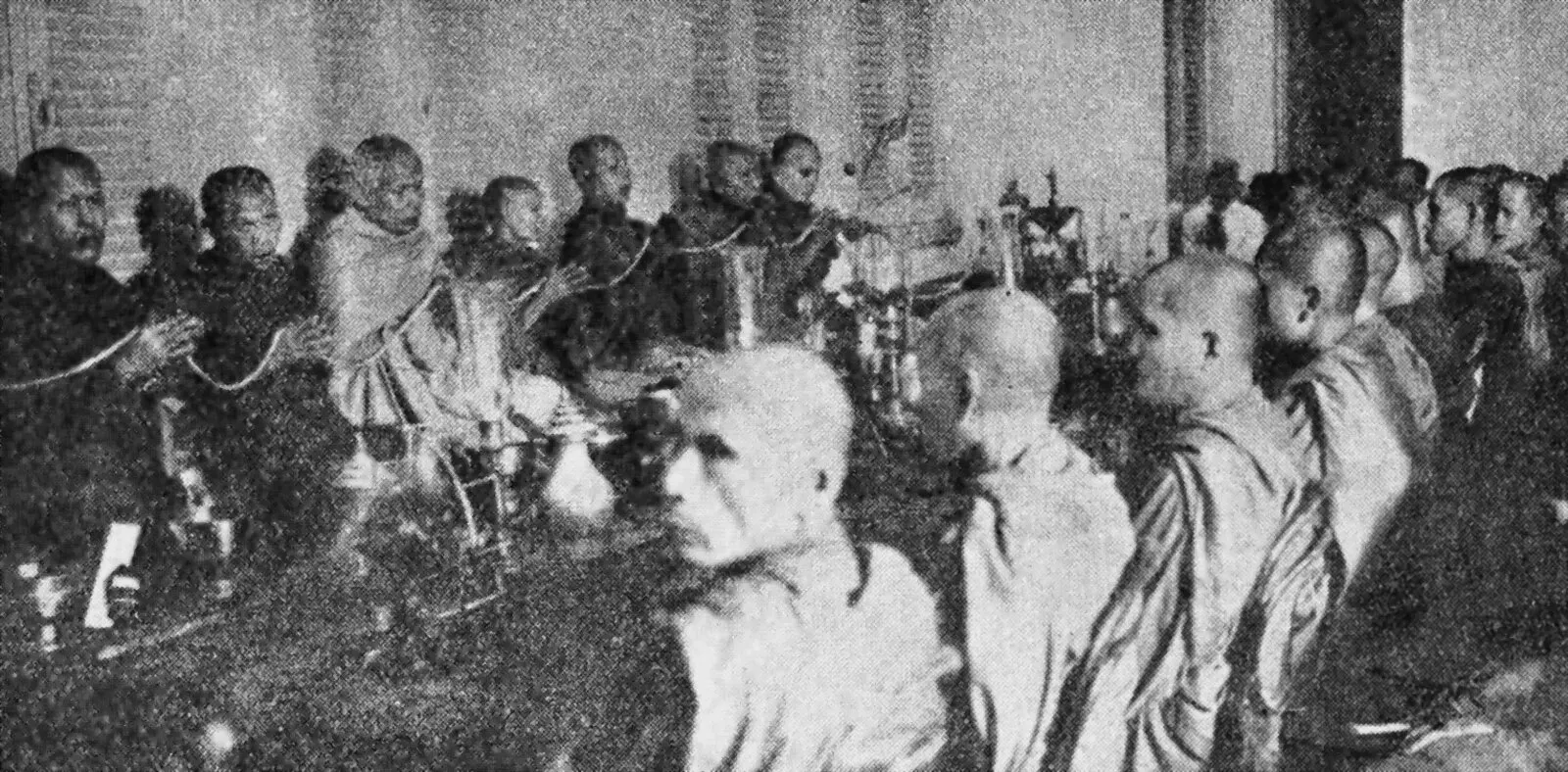 Czarno-białe zdjęcie mnichów buddyjskich siedzących w sali Instytutu Buddyjskiego w Phnom Penh w 1930 r.