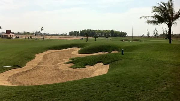 Fairway z bunkrem piaskowym i palmami na polu Grand Phnom Penh Golf Club pod Phnom Penh