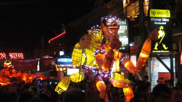 Podświetlone gigantyczne kukły niesione ulicą Siem Reap wieczorem